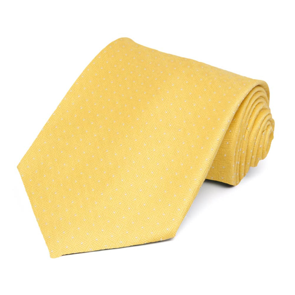 A yellow necktie with small white dots rolled to show the geometric texture