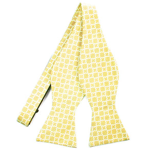 An untied light yellow self-tie bow tie with a white trellis pattern