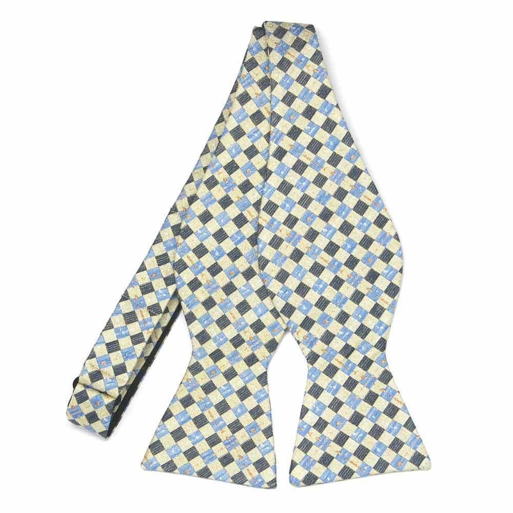 An untied soft yellow light blue and dark gray plaid self-tie bow tie